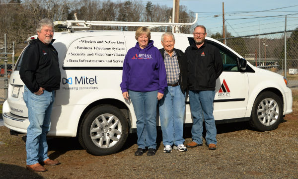 Four people standing in front of a white service van